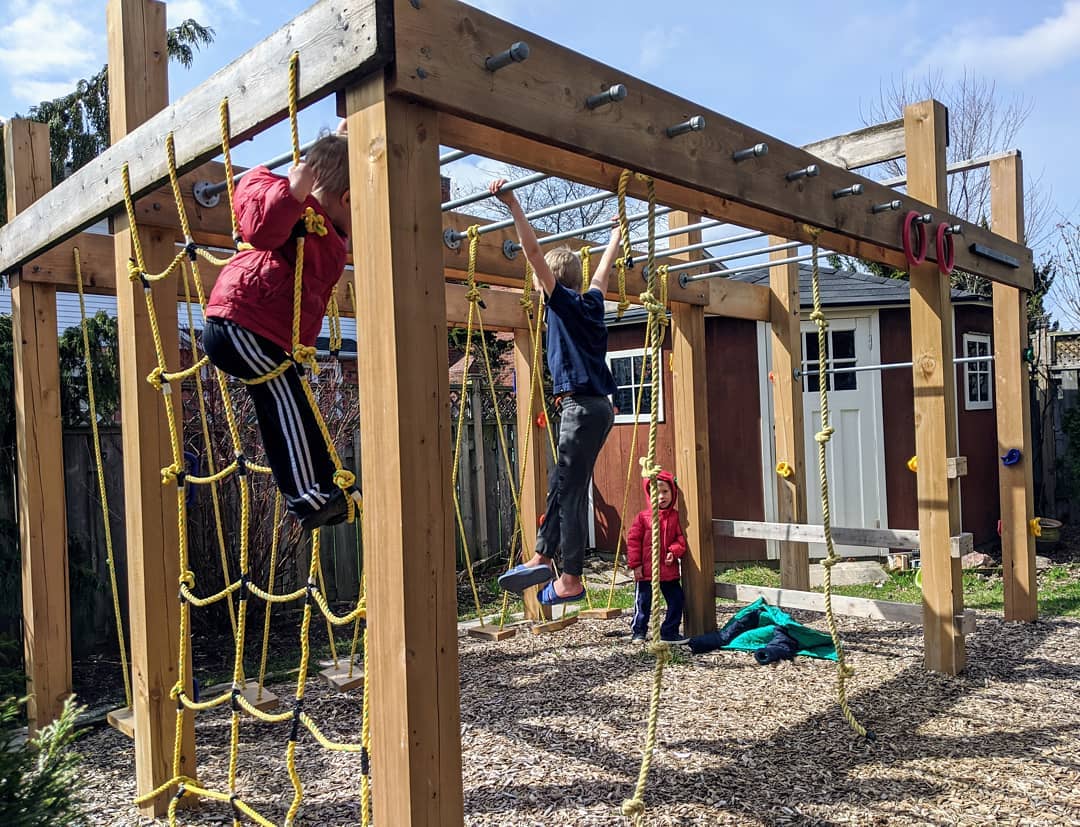 backyard playground with kids playing on monkey bars, cargo net, and ropes photo by Instagram user @midlifer32