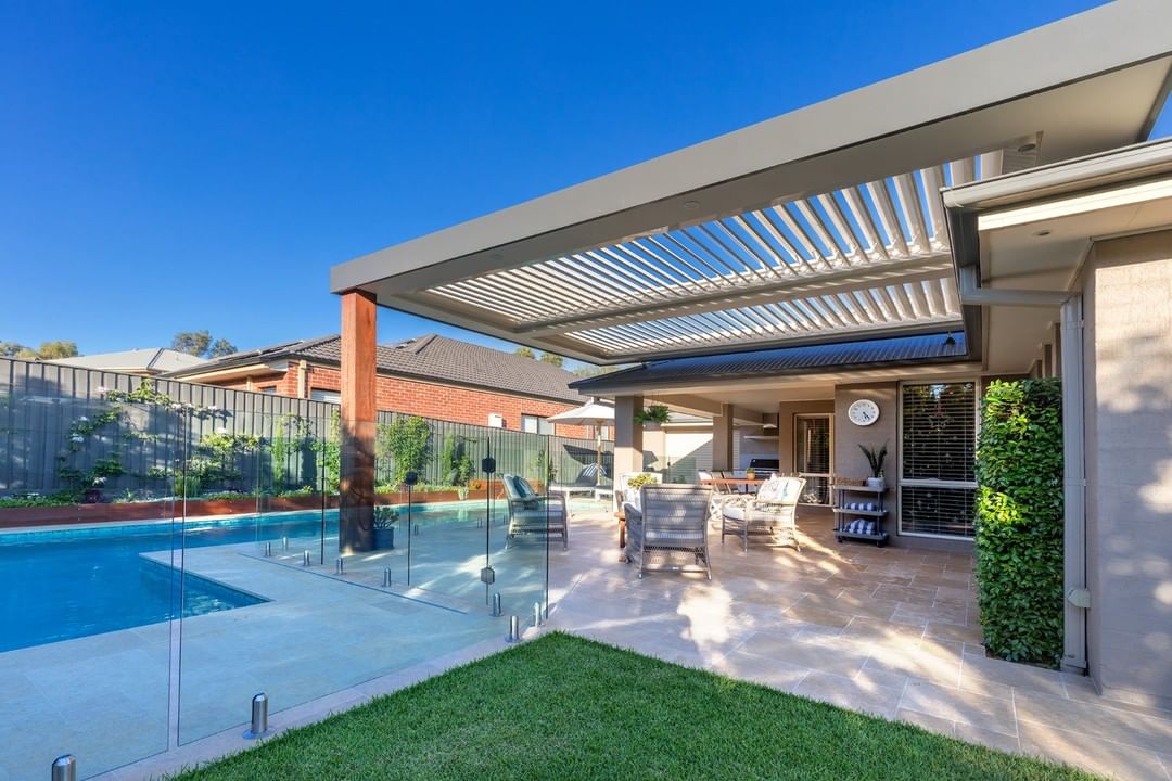 large home with big pergola over head and pool around photo by Instagram user @opening_roof_specialists