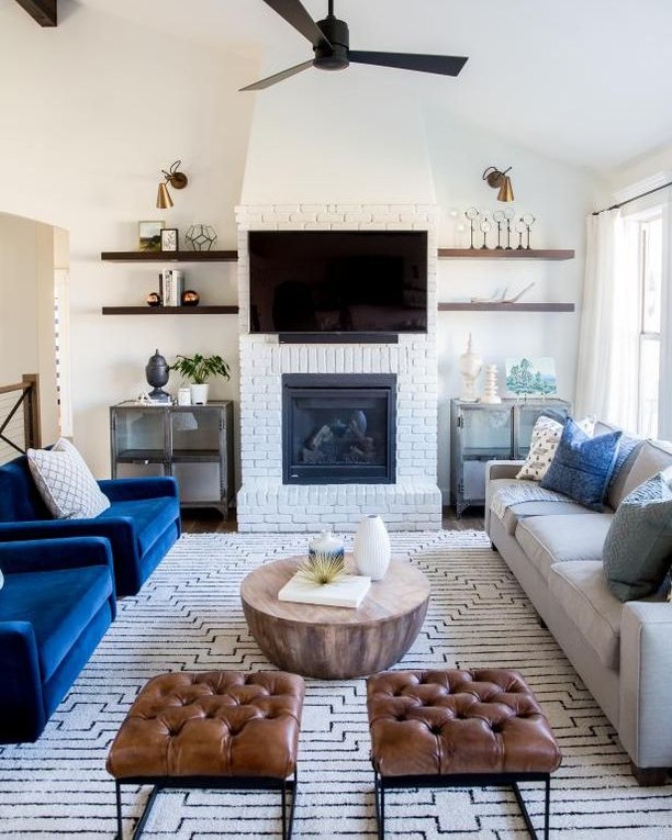 living room with fireplace that has been painted white and floating shelves installed next to it photo by Instagram user @marcpoulospainting