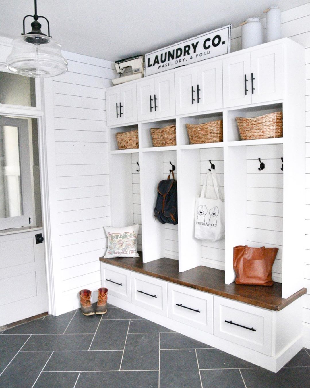 refurbished mudroom with new tile floors and white cabinets with black pulls photo by Instagram user @brunoandlibby