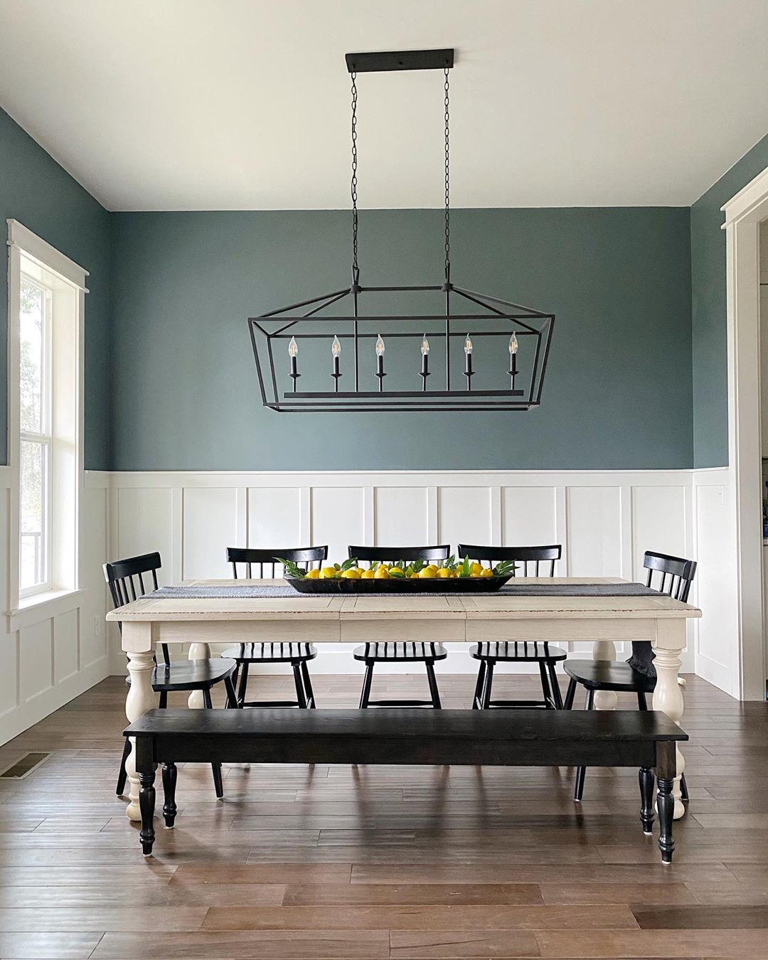 dining room with new light fixture, bench seating and new wall paneling photo by Instagram user @revivalhomedesigns