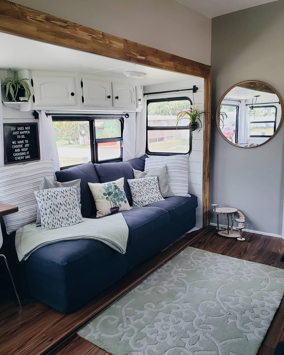 updated RV interior with gray and white walls and a blue couch photo by Instagram user @rvsandtrees