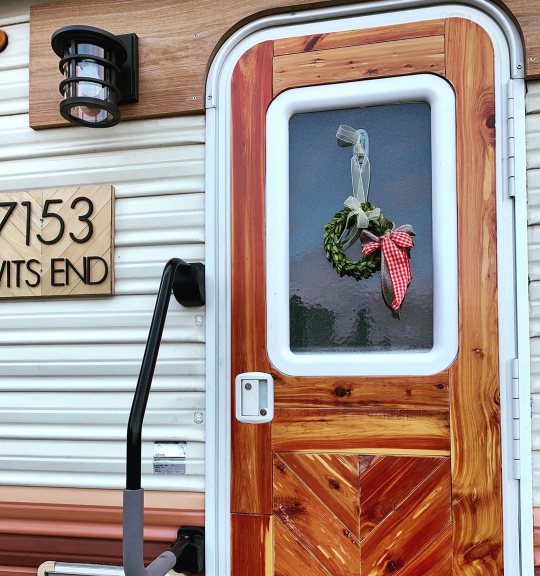 updated exterior of an RV with reclaimed wood on door and new porch light photo by Instagram user @robyns__nest__