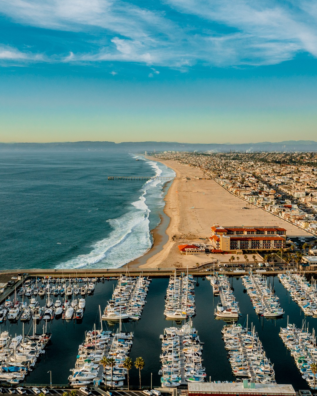Drone photo of Redondo Beach with a pier and boats. Photo by Instagram user @visionsbytombertolotti