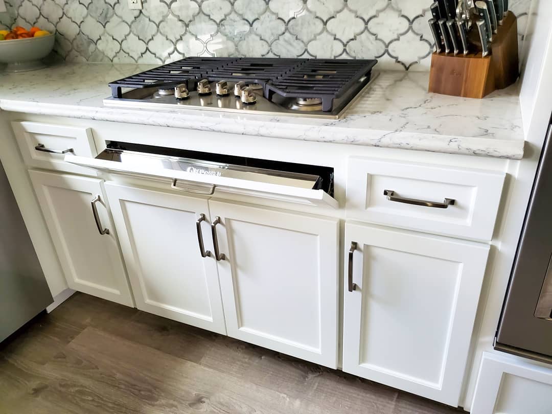 Countertop stove with tip out tray in front. Photo by Instagram user @jlcustomfinishes
