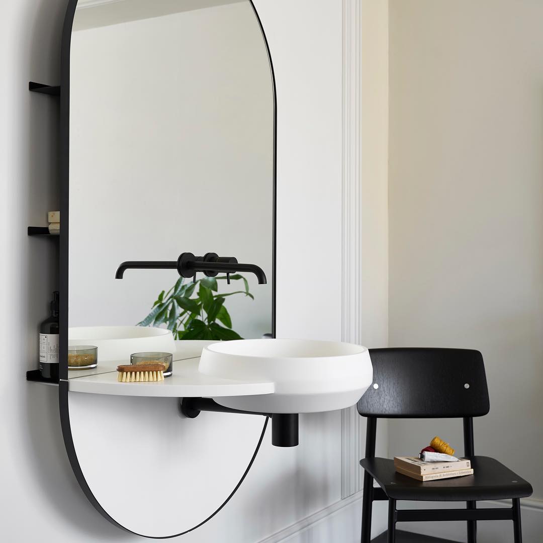 Small shelves hidden behind modern mirror attached to bathroom sink. Photo by Instagram user @westonebathrooms