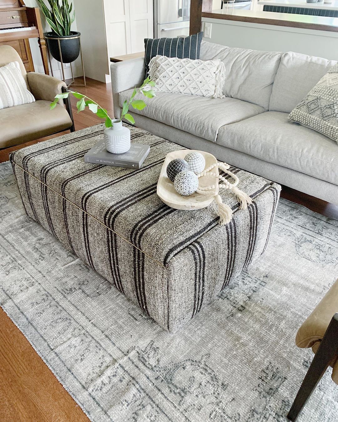 Storage Ottoman placed in the middle of a living room. Photo by Instagram user @courtneyungaro_spaceanddesign
