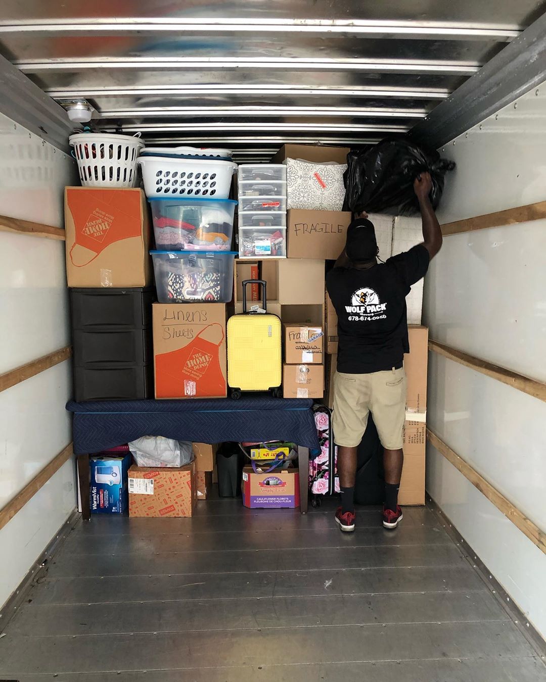 Man Packing Boxes into Moving Truck. Photo by Instagram user @wolfpackmovers