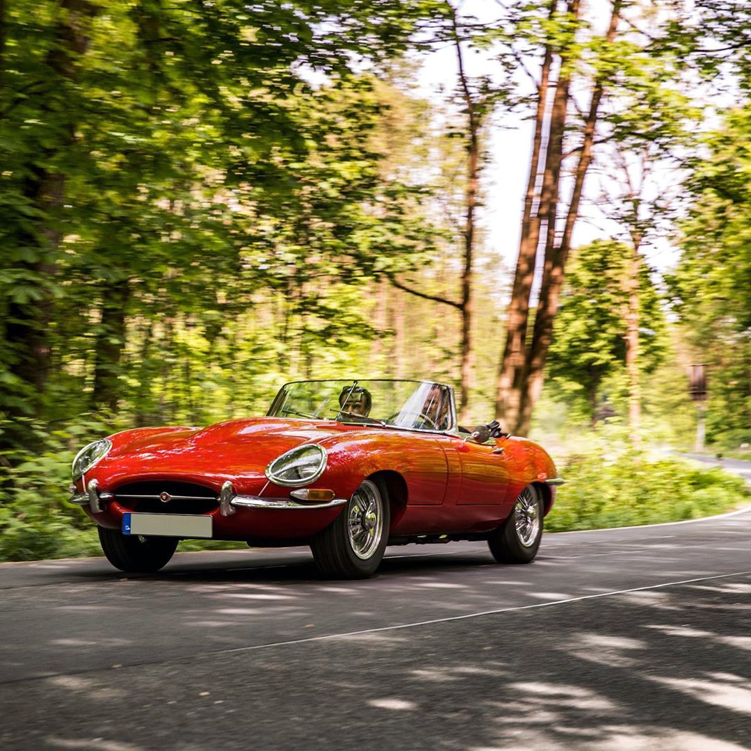 Two Men Driving a Classic Red Jaguar. Photo by Instagram User @broadpeak_car_storage