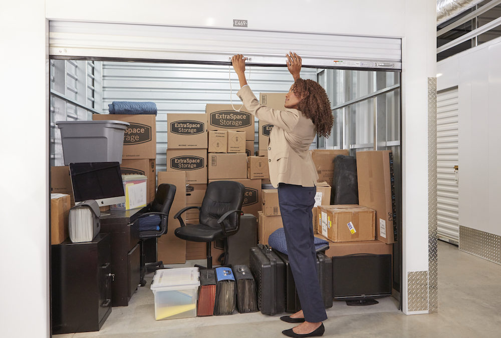 Black Woman Closing the Door of her Self Storage Unit with Boxes Inside