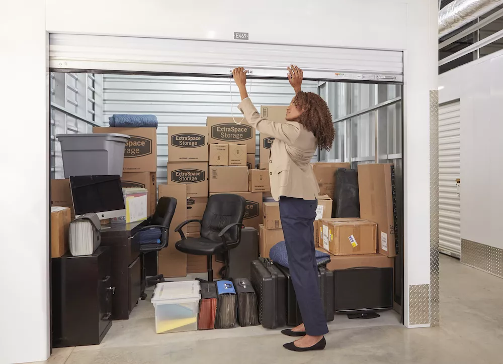 Black Woman Closing the Door of her Self Storage Unit with Boxes Inside