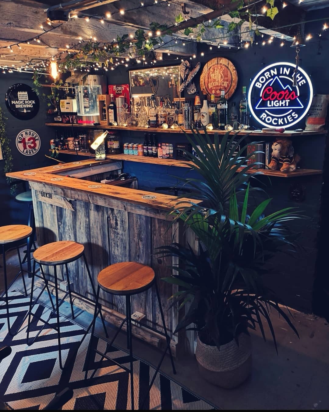 Classic Home Bar Setup with Drinks on the Wall and Light Up Coors Light Sign. Photo by Instagram user @one_two_miss_a_few