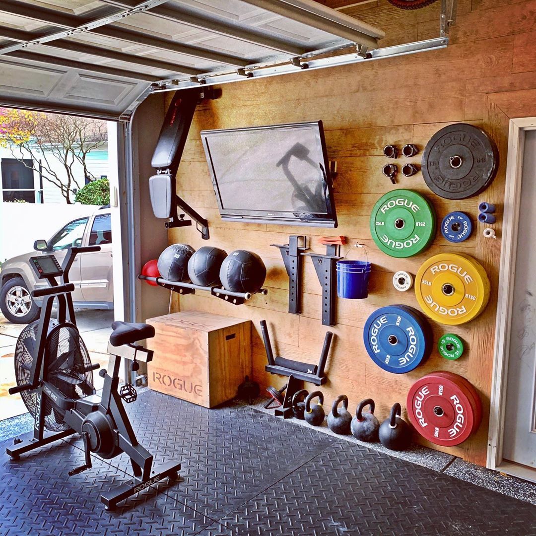 Garage Gym Setup with Weights on the Wall and Assault Air Bike Set Out. Photo by Instagram user @jmlwoodcraft