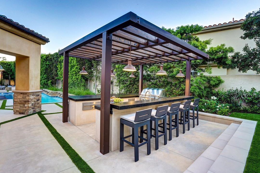 Outdoor Kitchen with Pergola and Barstools Next to Counter. Photo by Instagram user @pacificstonedesign
