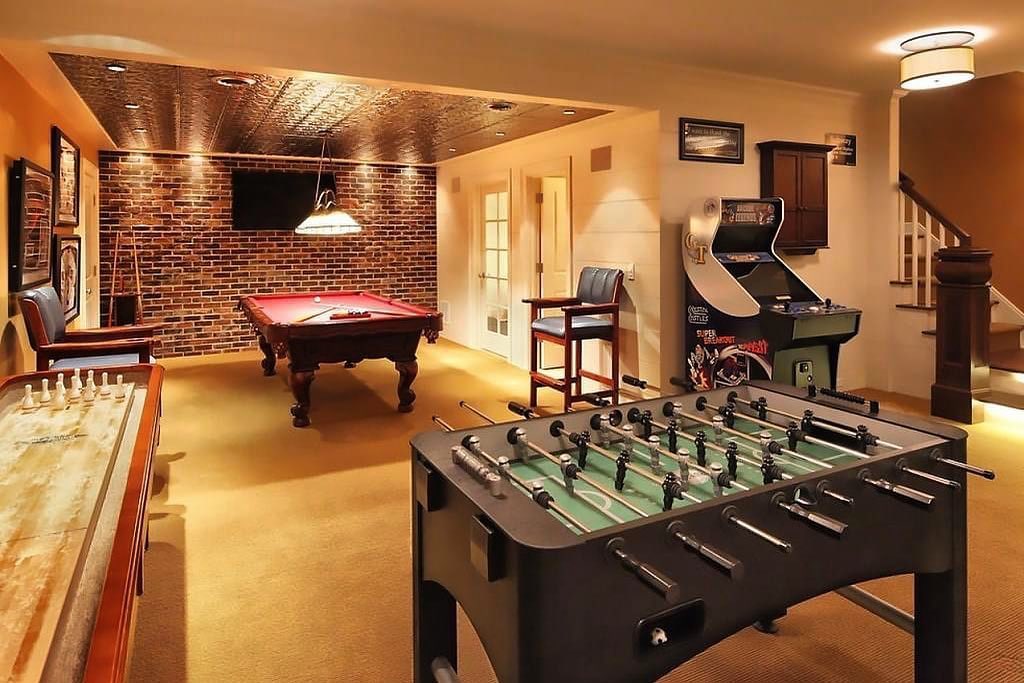Finished Basement Filled with a Pool Table, Shuffleboard Table, Foosball, and Arcade Game. Photo by Instagram user @mancavemasters