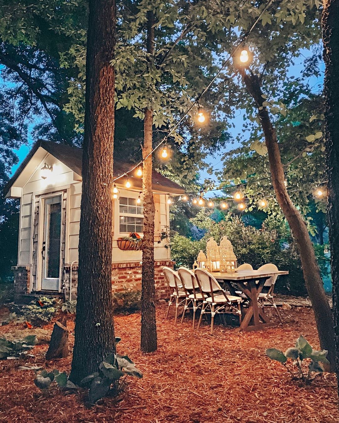 Small She Shed in the Trees with a Table and Chairs Nearby. Photo by Instagram user @cottonstem
