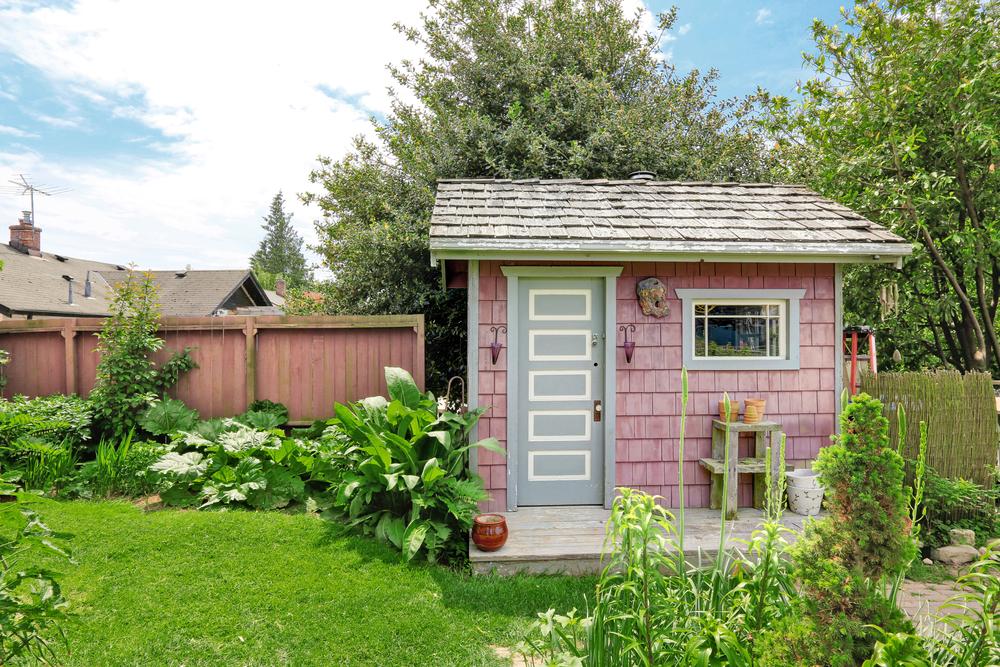 Pink She Shed in a Back Yard with Nice Landscaping Nearby