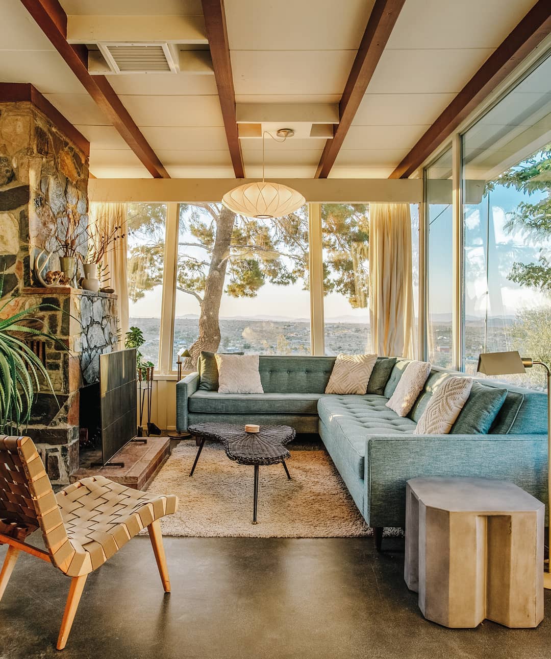 Home with Large Windows Surrounding Living Room Looking Out to the Yucca Valley. Photo by Instagram user @jtreebnb