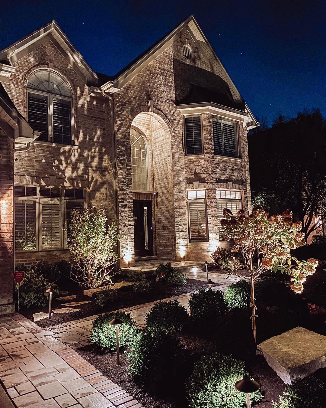 Large Brick House with Landscape Lighting. Photo by Instagram user @lizflowersinteriors