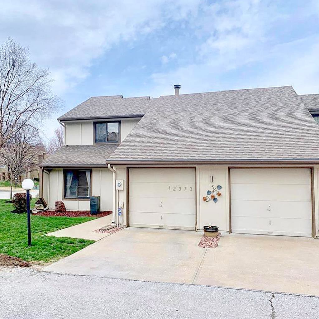 A photo of a white, two-car garage home with a green yard in Mission Lake, Kansas City. Photo by Instagram user @kcdiscountrealtor.