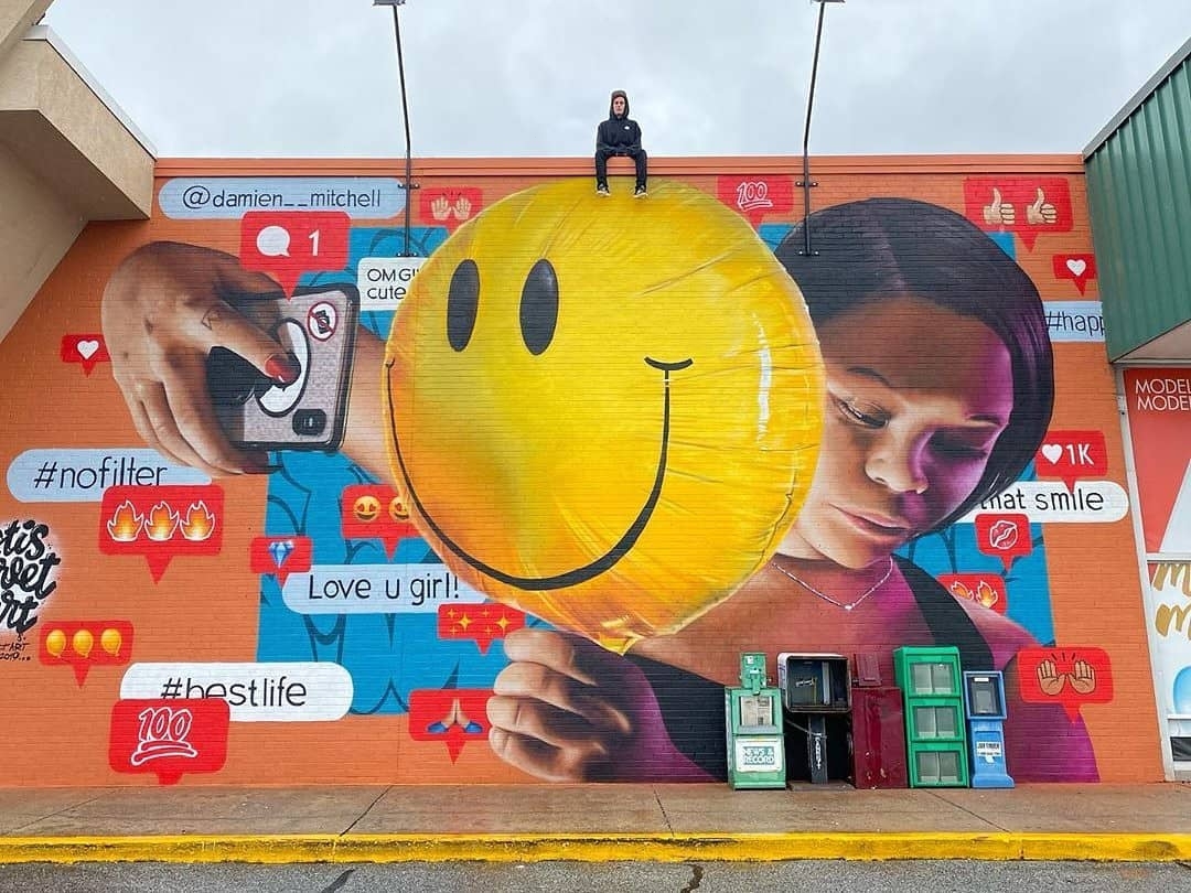 Young Teen Sitting On Top of a Large Art Mural. Photo by Instagram user @topstreetart