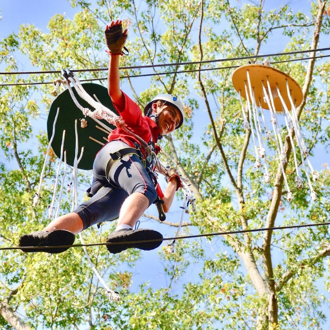 Woman on a High Ropes Course at the Greensboro Science Center on a Nice Day. Photo by Instagram user @greensborosciencecenter