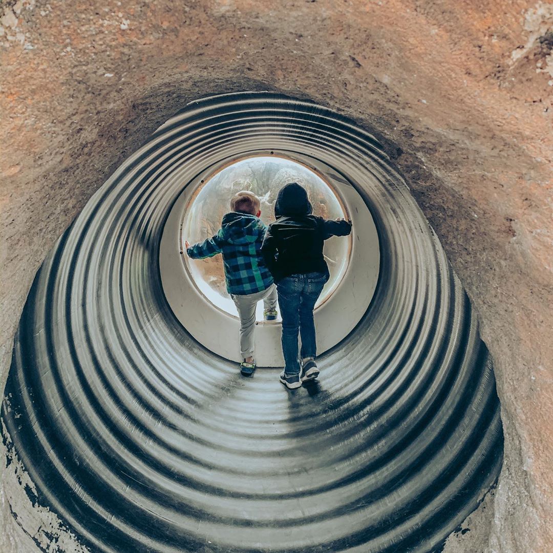 Two Young Kids Walking Through a Small Tunnel to See More Animals at the Zoo. Photo by Instagram user @crazysweetchaos