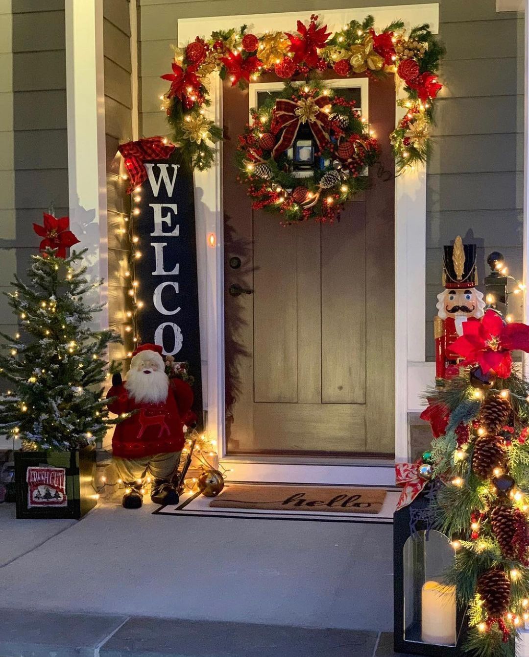 A front porch lights up to reveal a Santa Claus statue on one side of the door, and a nutcracker on the other. Photo by Instagram user @nhomedesignideas.