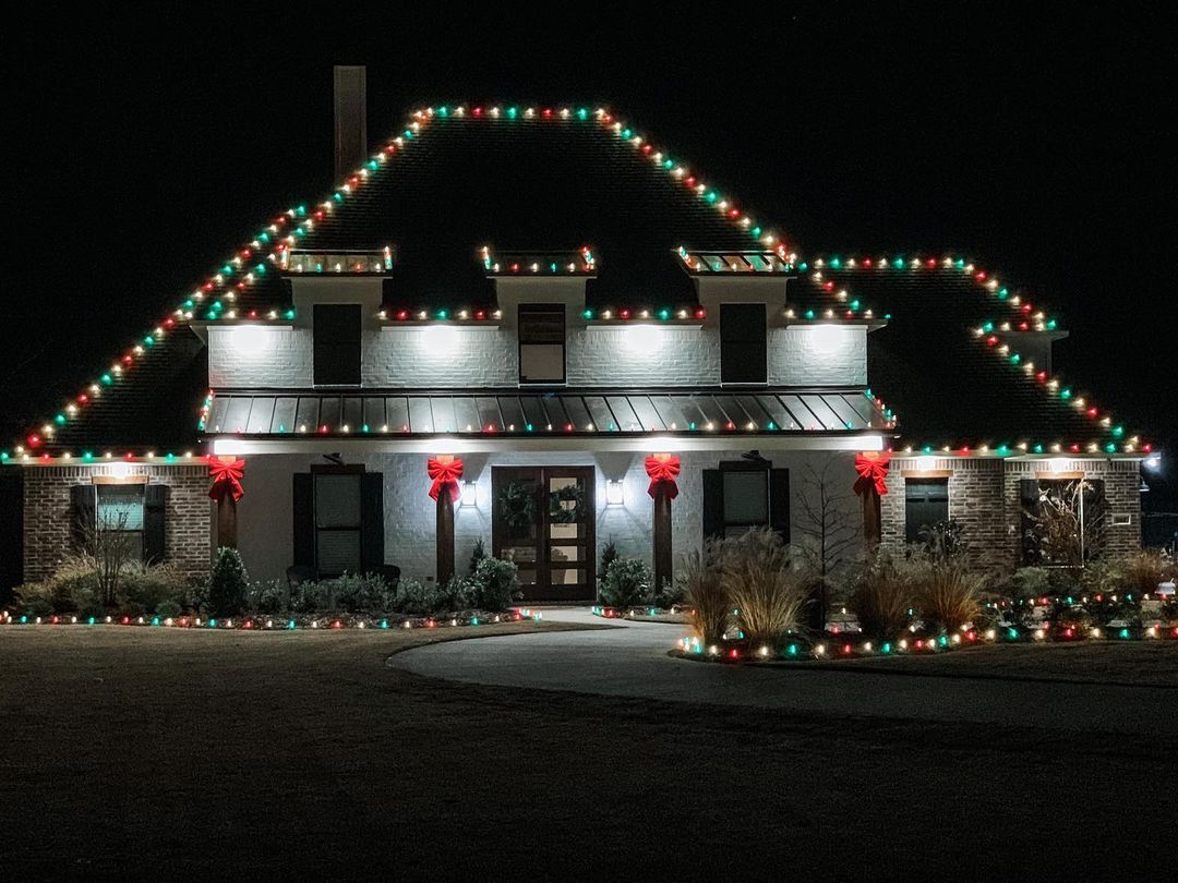 Christmas lights on the edges of a house's roof and landscape at night. Photo by Instagram user @casadethompson