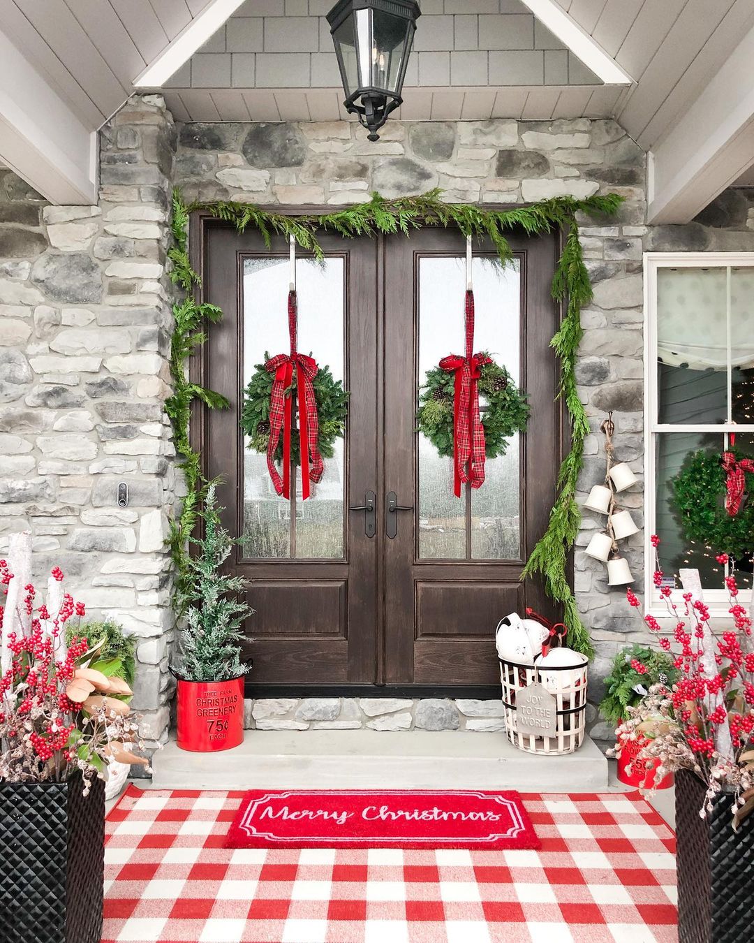 Double front doors lined with garland and two wreathes hanging on the door windows. Photo by Instagram user @beyond_gray.