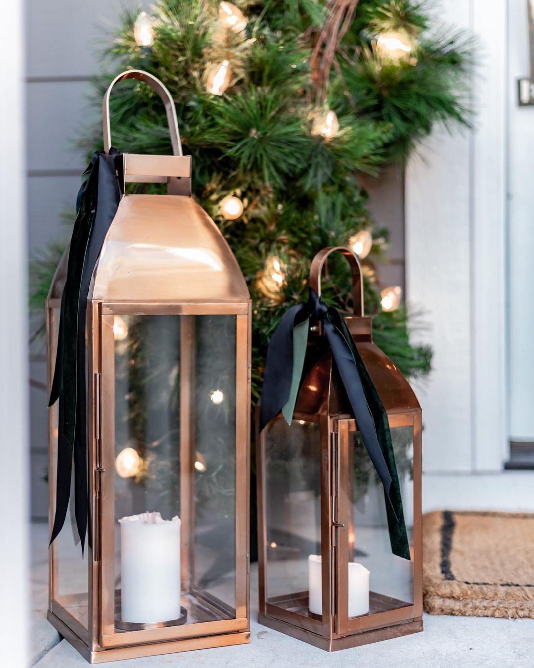 Two bronze lanterns hold a candle outside. Photo by Instagram user @hegraycottage