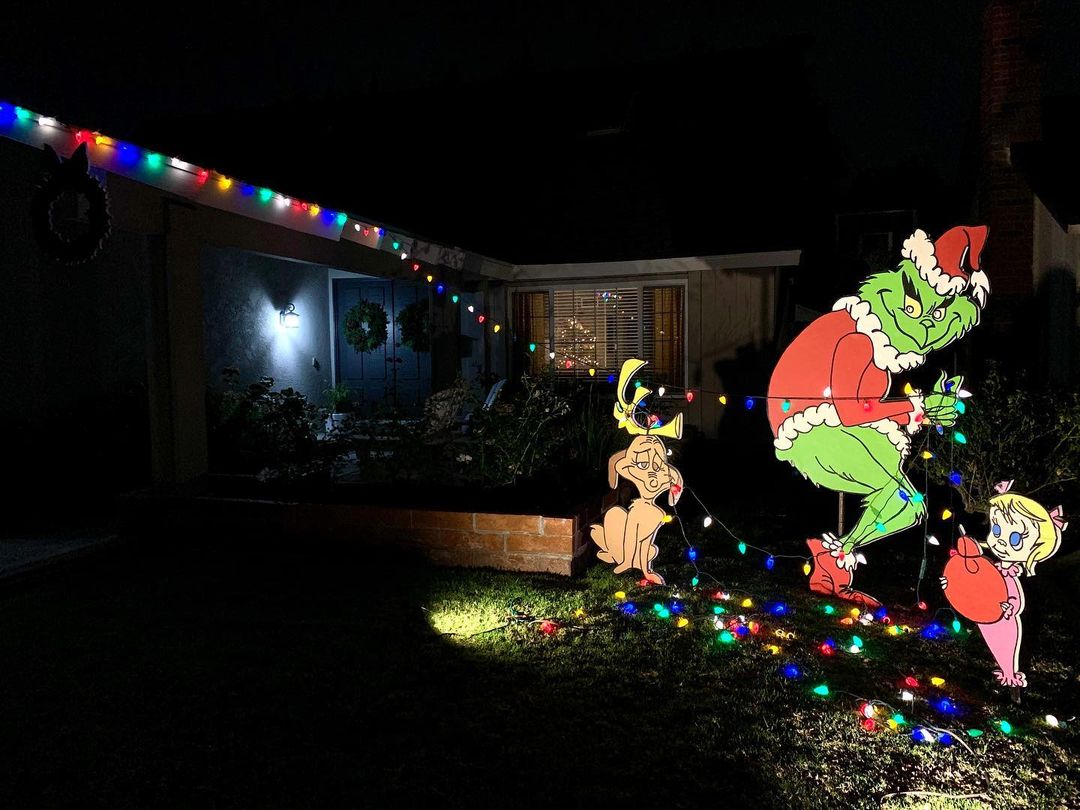 At night, a large cut out of the classic Grinch tiptoes away from the house, stealing the Christmas lights. Photo by Instagram user @kitrae.