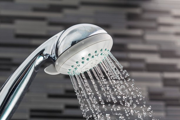 Low-flow shower head in a gray tiled shower. Photo by Instagram user @tamarapulstsrealtor