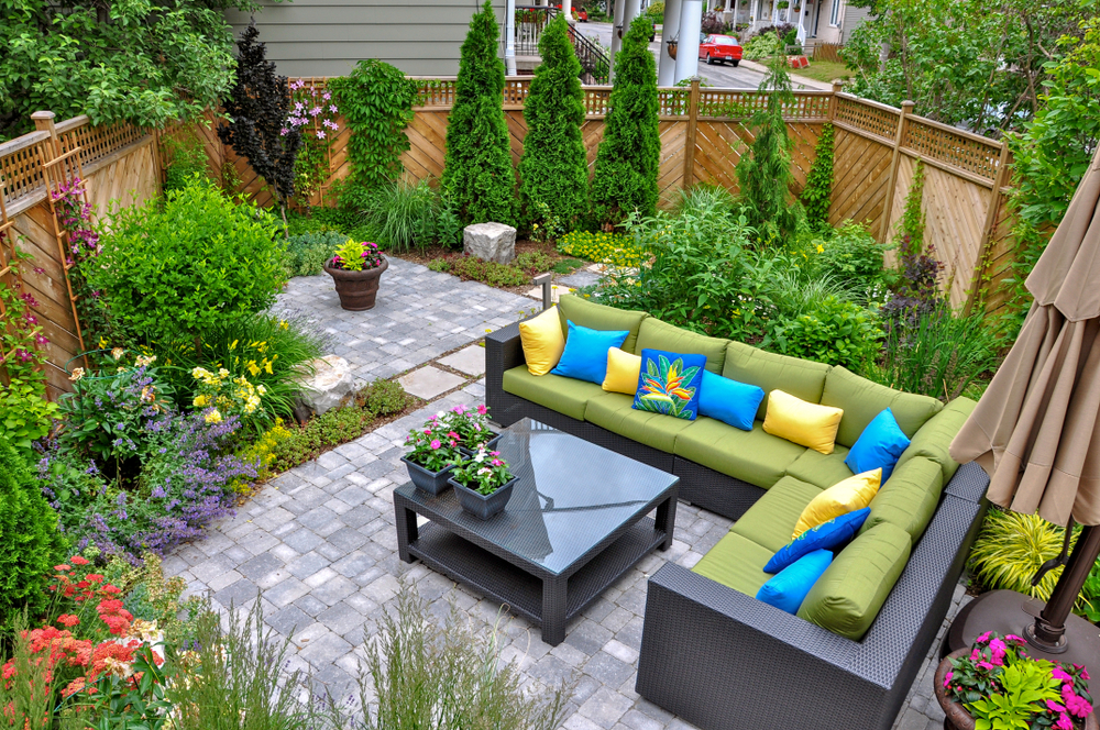 An aerial view of a fenced in backyard with patio furniture and table atop of stone pavers