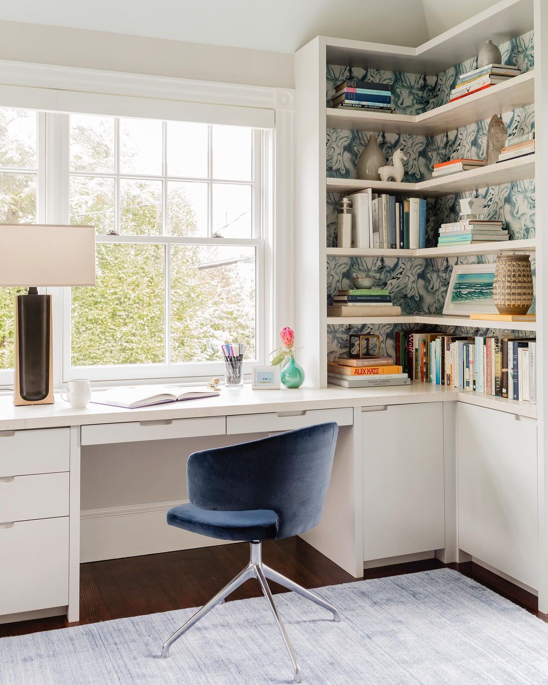A home office with large windows and floor to ceiling shelving. Photo by Instagram user @deeelms