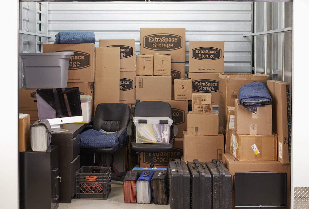 ExtraSpace Storage unit filled with office furniture and moving boxes.