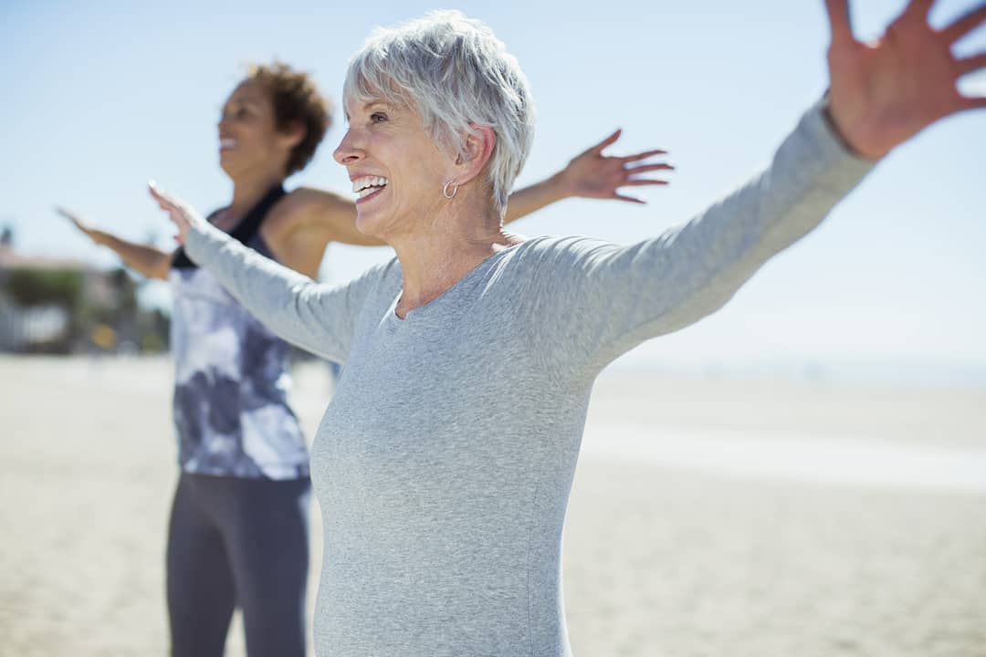 Older Woman Doing Yoga on the Beach. Photo by Instagram user @aetna