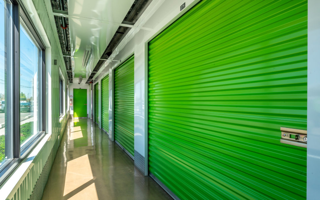 View down a hallway of an Extra Space Storage facility; hallways is clean, well-lit, and has bright green garage-like doors