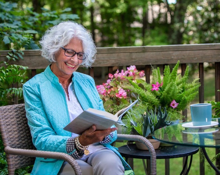 Older Woman Sitting on Her Deck Reading a Book. Photo by Instagram user @brookdaleliving