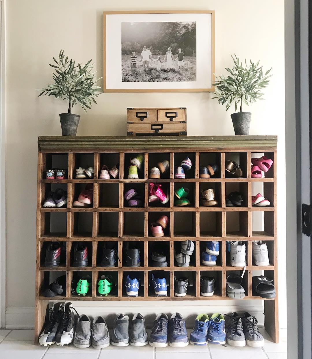 Cubbies holding several pairs of shoes in home entryway.