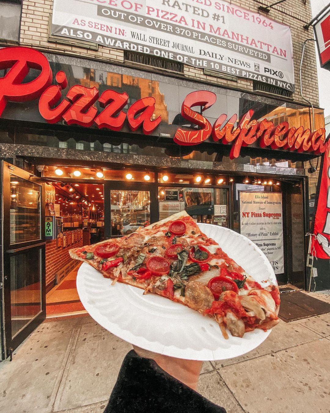 Person Holding a Piece of New York-Style from NY Pizza Suprema. Photo by Instagram user @catcybul