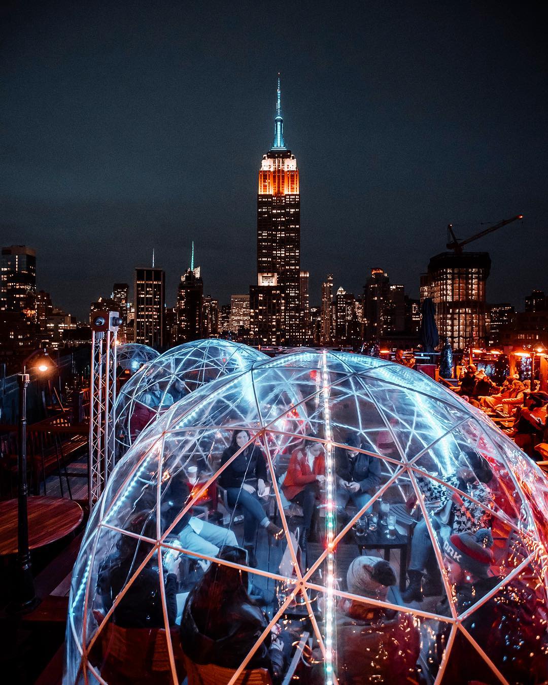 New York City building rooftop with people sitting inside heated plastic domes. 