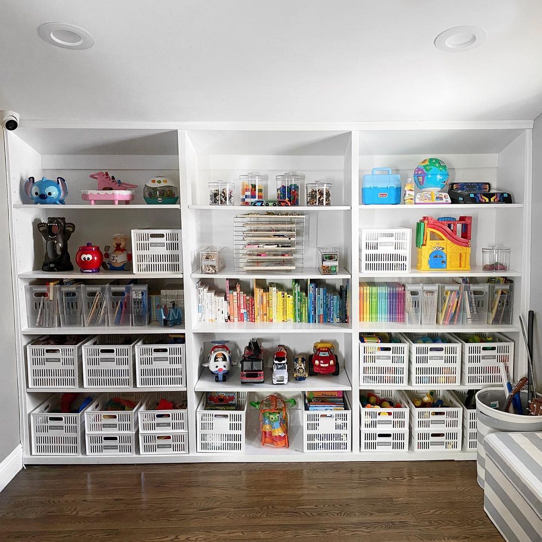 Floor-to-ceiling bookshelves with bins filled with toys, and various larger toys on other shelves. Photo by Instagram user @theorganizingblonde.