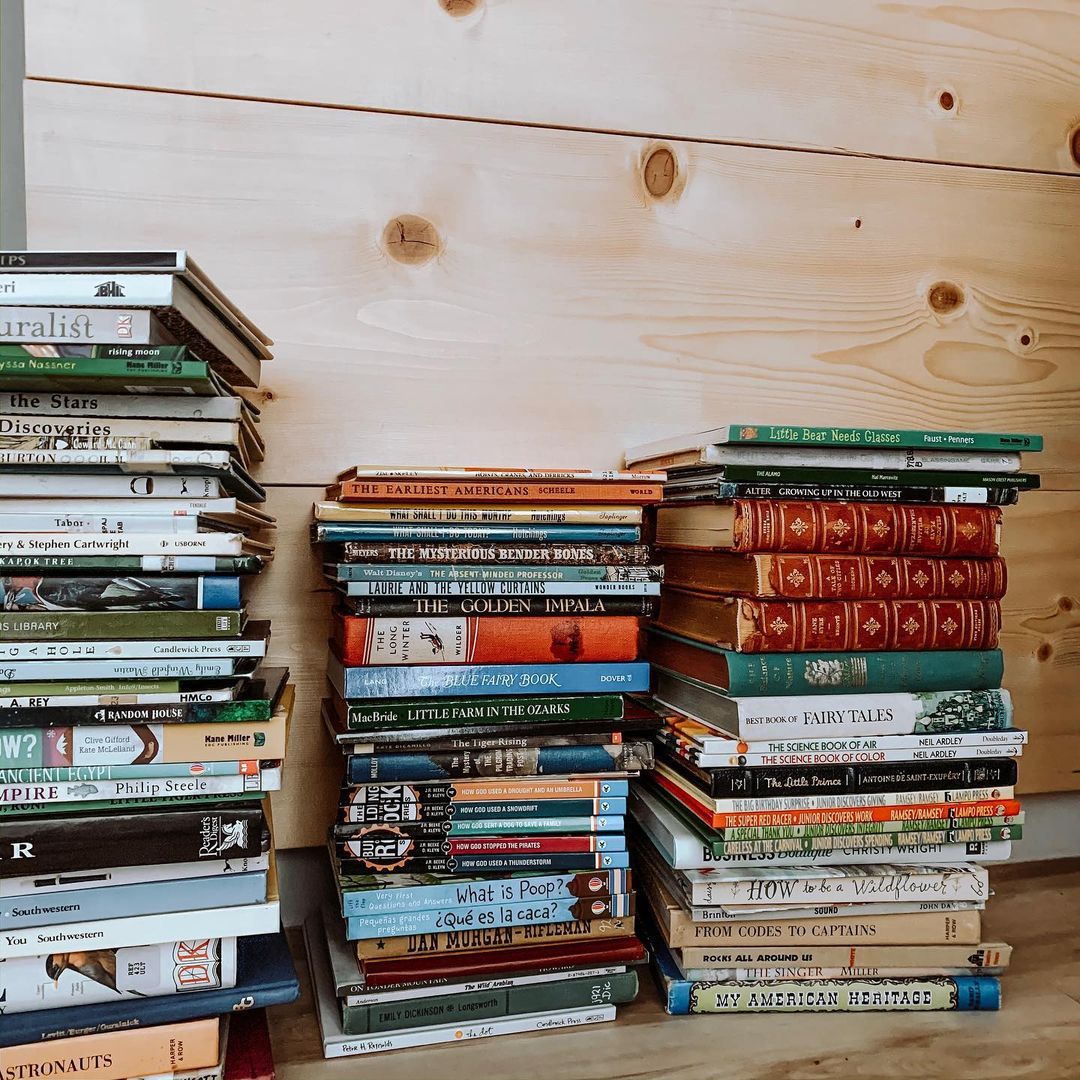 Three stacks of books on the floor. Photo by Instagram user @wearetheolivers_.