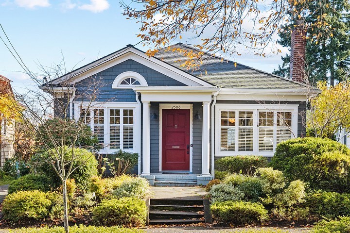 Exterior of blue bungalow home with white trim and red door in Seattle, WA