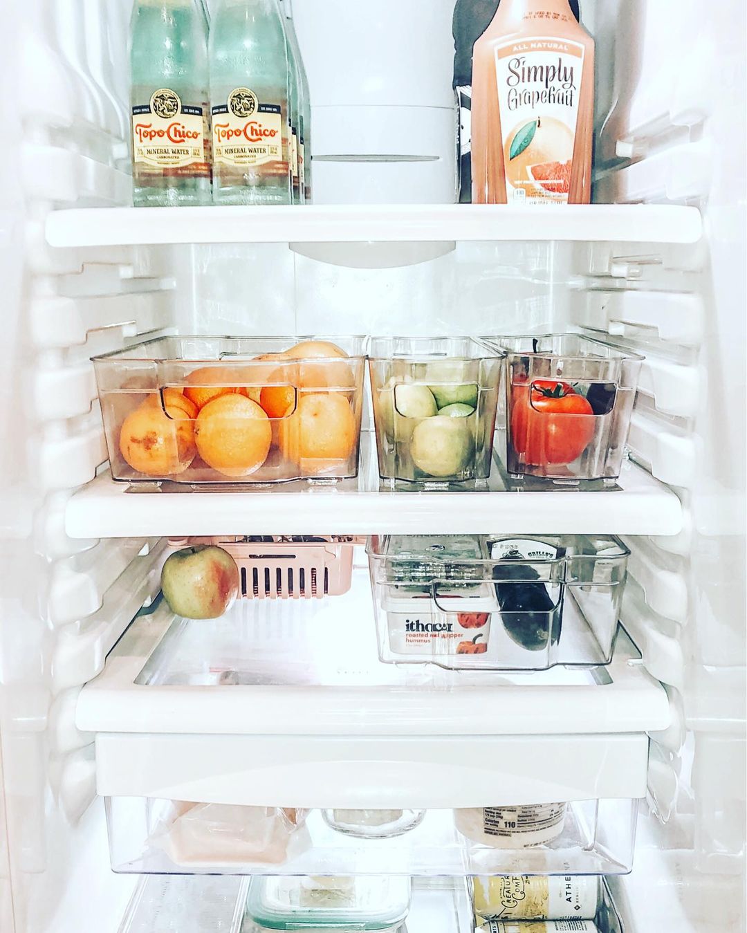 Organized fridge using clear plastic bins to hold items. Photo by Instagram user @jennycannady