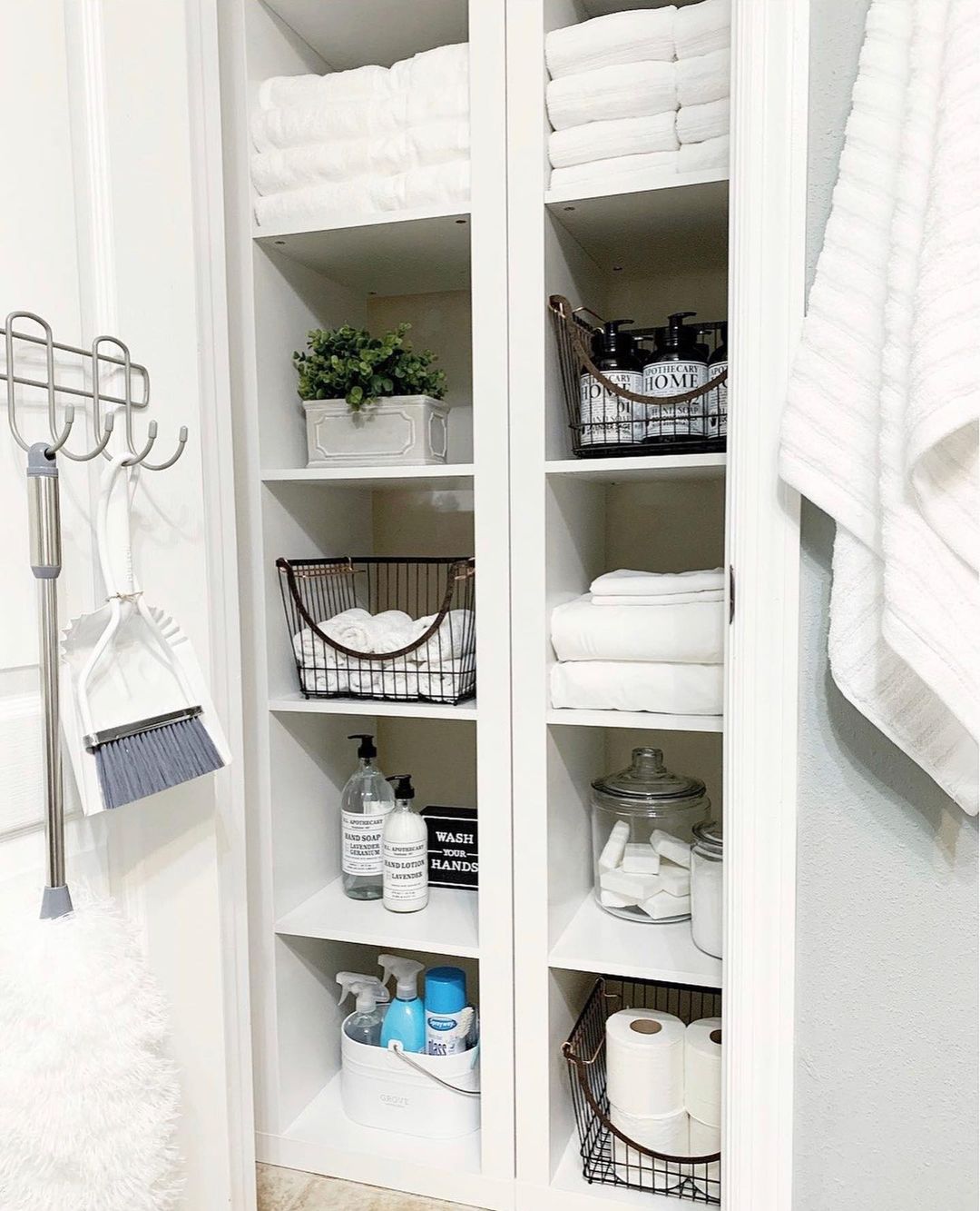 Linen closet organized with glass containers, baskets, and bins. Photo by Instagram user @bemyguestwithdenise