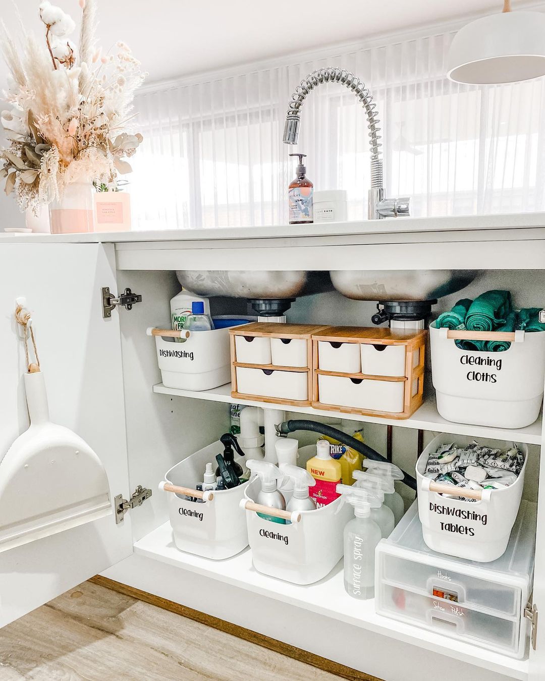 Under sink cabinet organized with shelving and storage bins. Photo by Instagram user @ashleejayinteriors