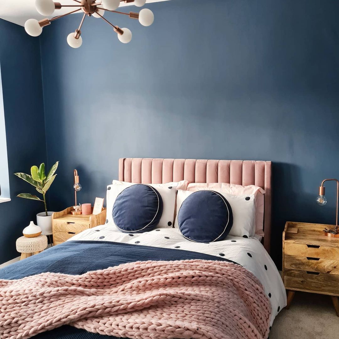 View of bed with a navy wall in the back.