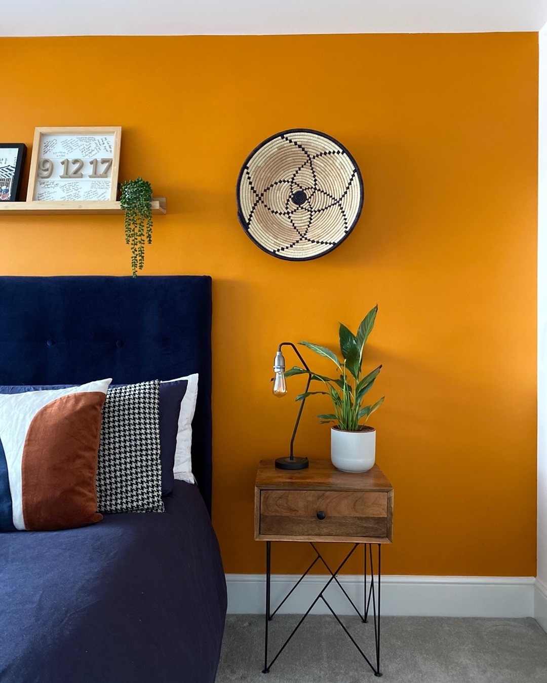 Deep navy bed against a bright orange wall.